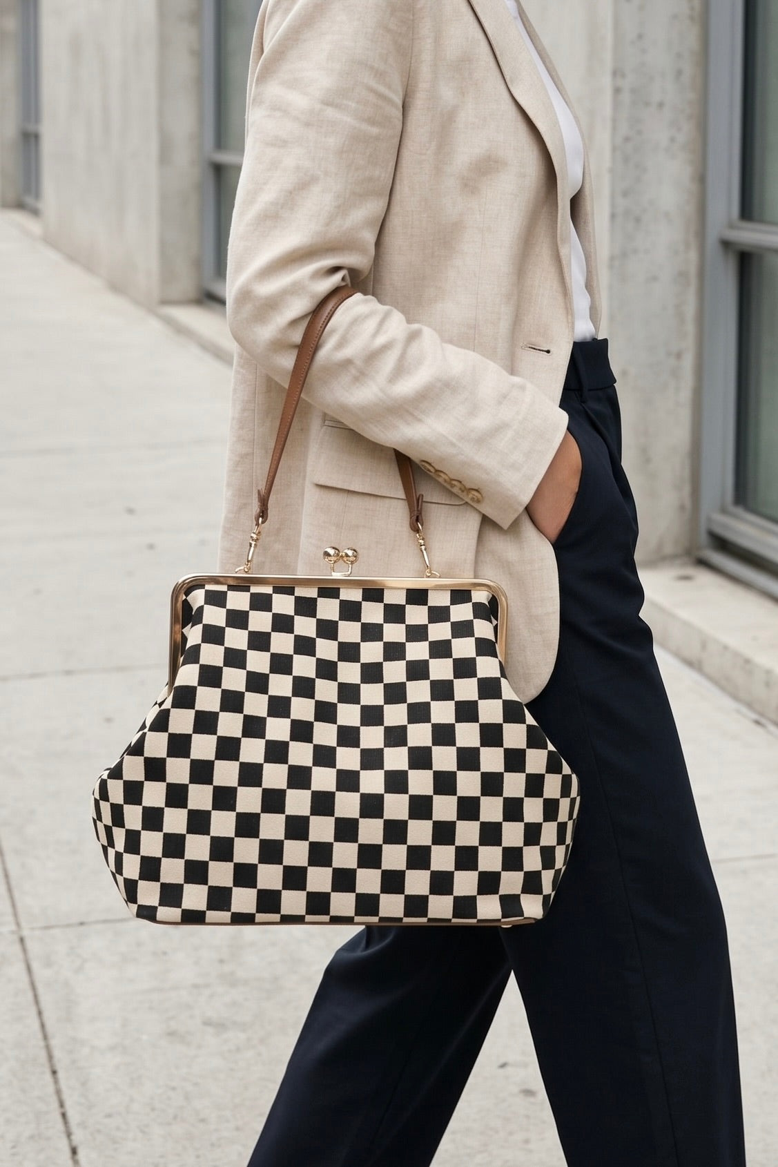 Black and ivory checkerboard shoulder handbag with gold-tone kiss lock frame and brown shoulder strap.