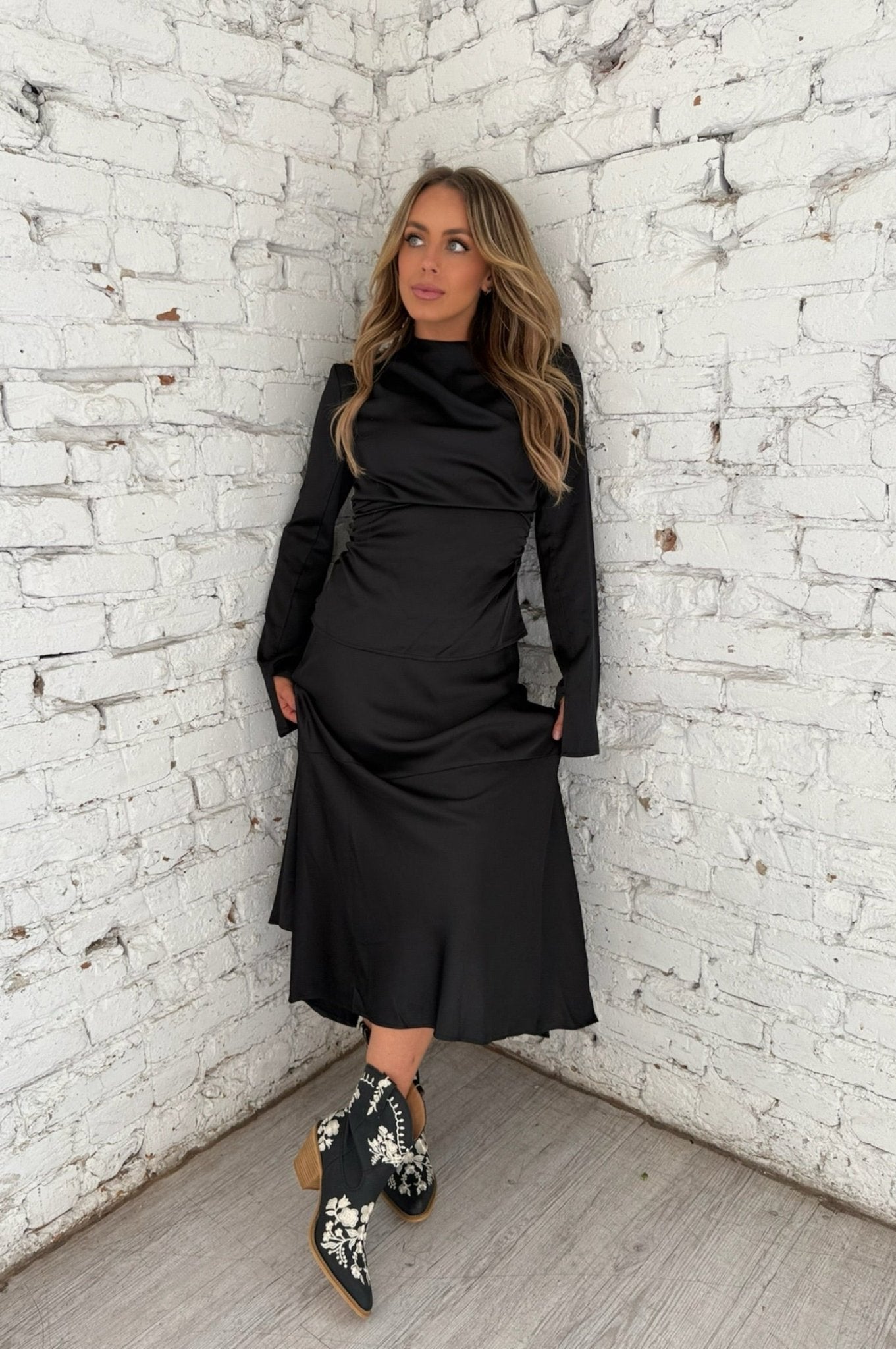 Elegant black satin midi skirt with flowy hem and matching ruched top