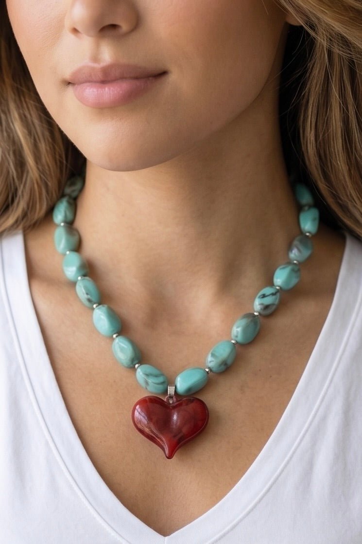 Statement beaded necklace featuring glossy burgundy beads and an oversized turquoise marbled heart pendant with an adjustable clasp. Available in three color variations.