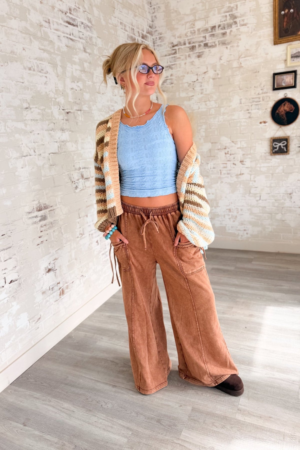 Women’s rust brown washed wide leg pants featuring a relaxed fit, elastic drawstring waistband, oversized front patch pockets, contrast seam detailing and a soft lived-in finish. Casual pull-on pants with a loose straight wide leg silhouette for boho, casual, lounge and everyday outfits.