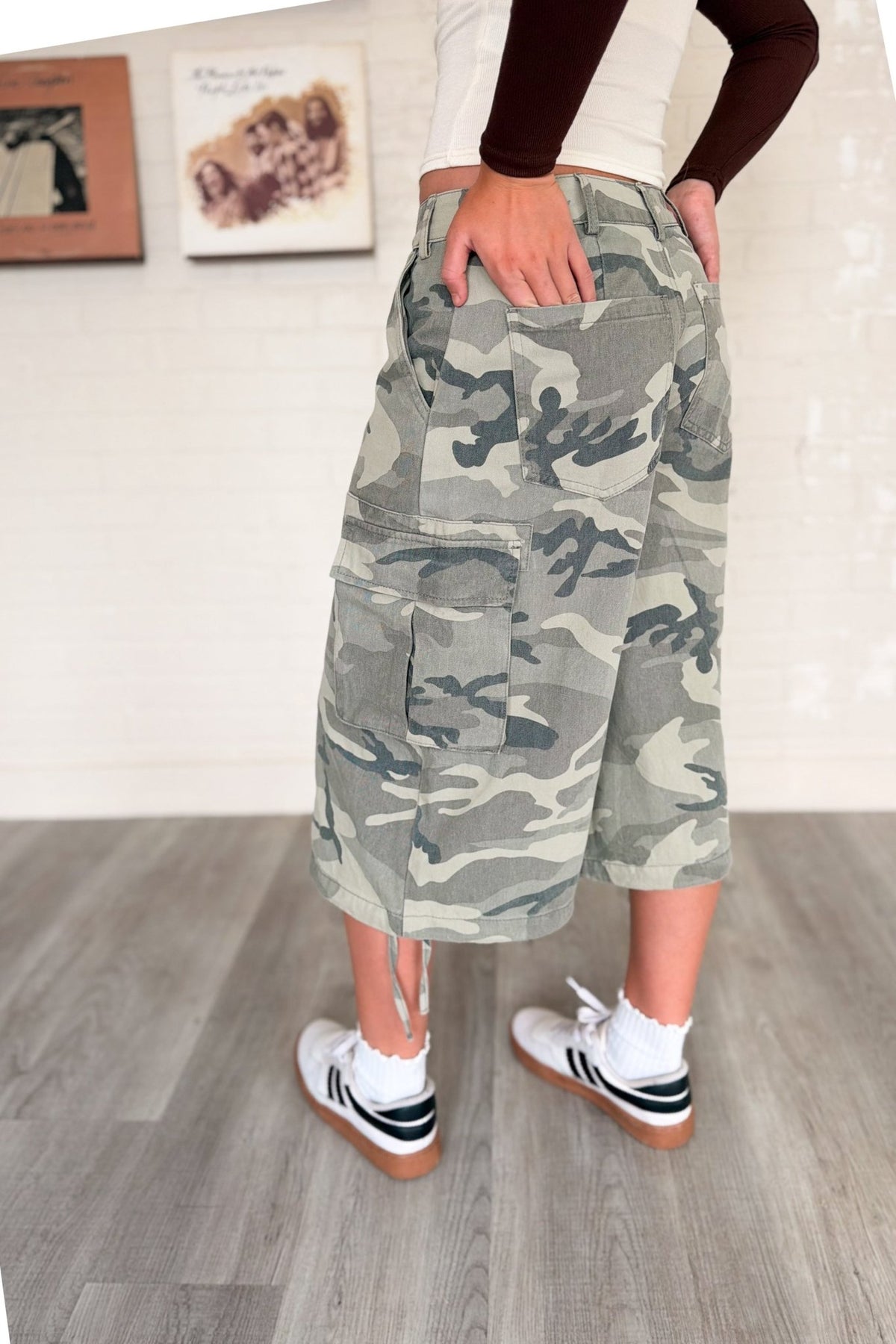 Women’s washed gray and sage camouflage cargo culotte jorts with a low-rise waist, oversized wide-leg below-the-knee silhouette, side flap utility pockets and adjustable drawstring hems.