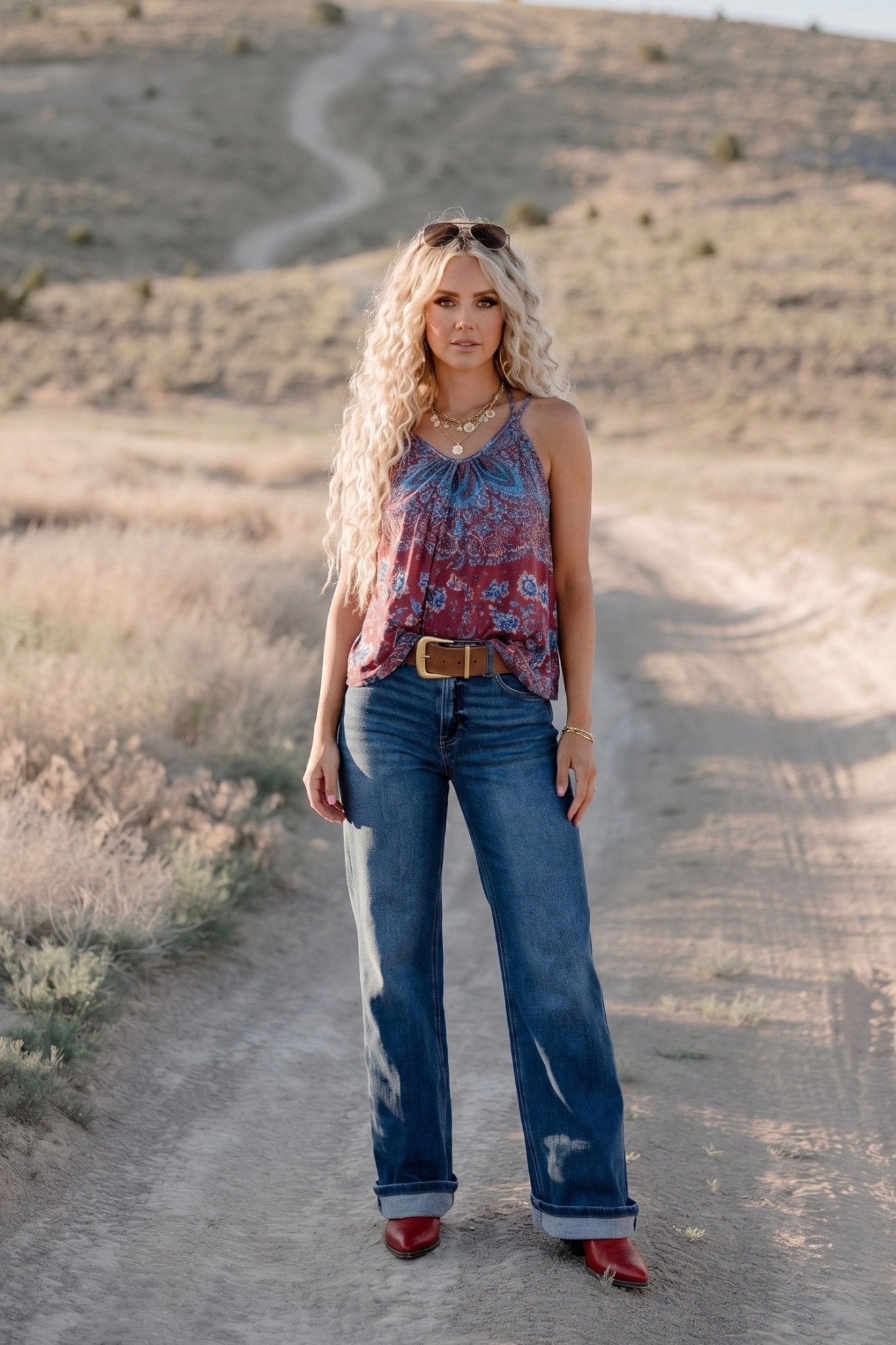 Flowy boho tank featuring a blue and rust paisley print, V-neckline, tie-front detail, and thin shoulder straps.