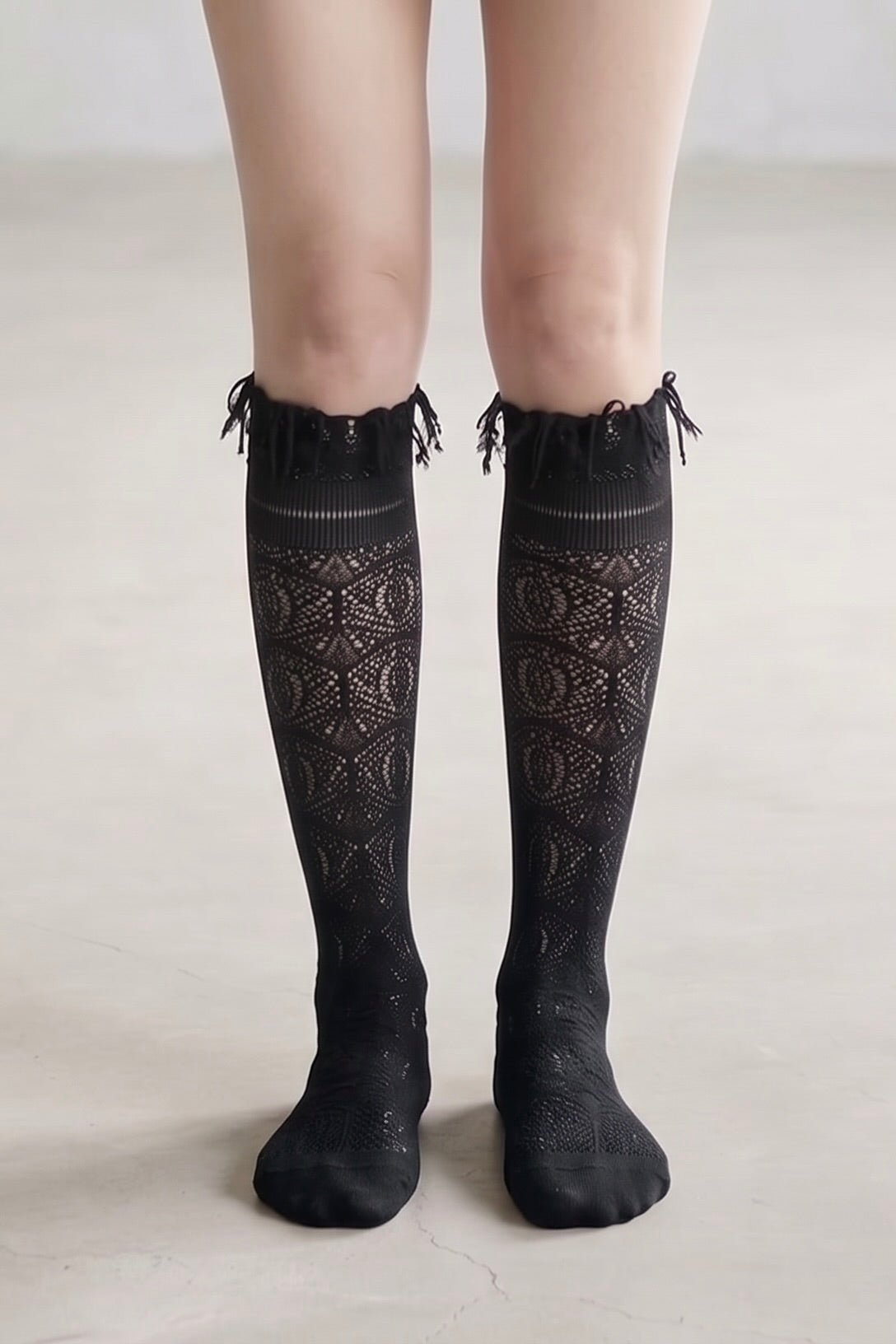 Wine sheer jacquard lace knee-high socks with intricate openwork pattern and tassel trim styled with black pointed heels.