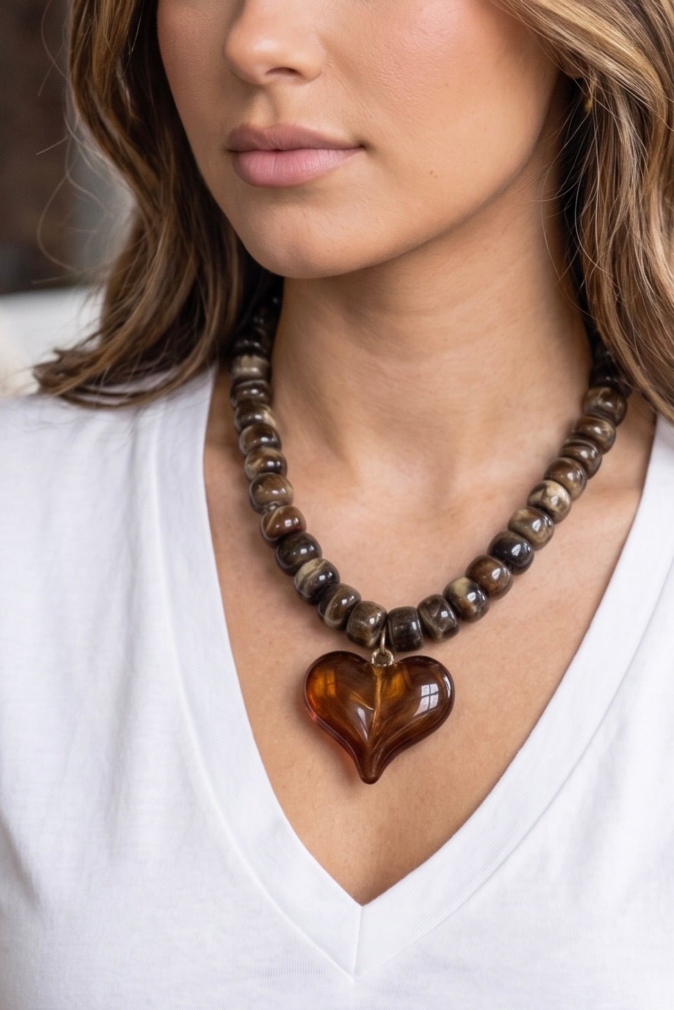 Marbled mocha bead statement necklace featuring an oversized translucent amber heart pendant with an adjustable gold-tone chain.