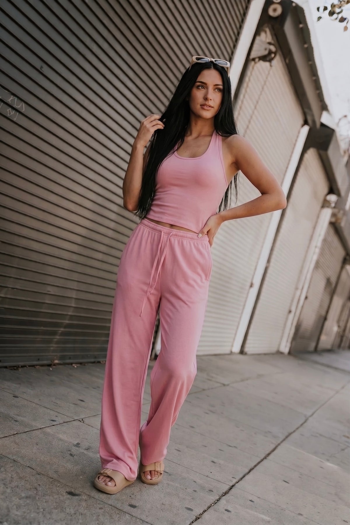 Pink two-piece lounge set with V-neck racerback crop tank and high-waisted wide-leg pants with drawstring waist and side pockets.