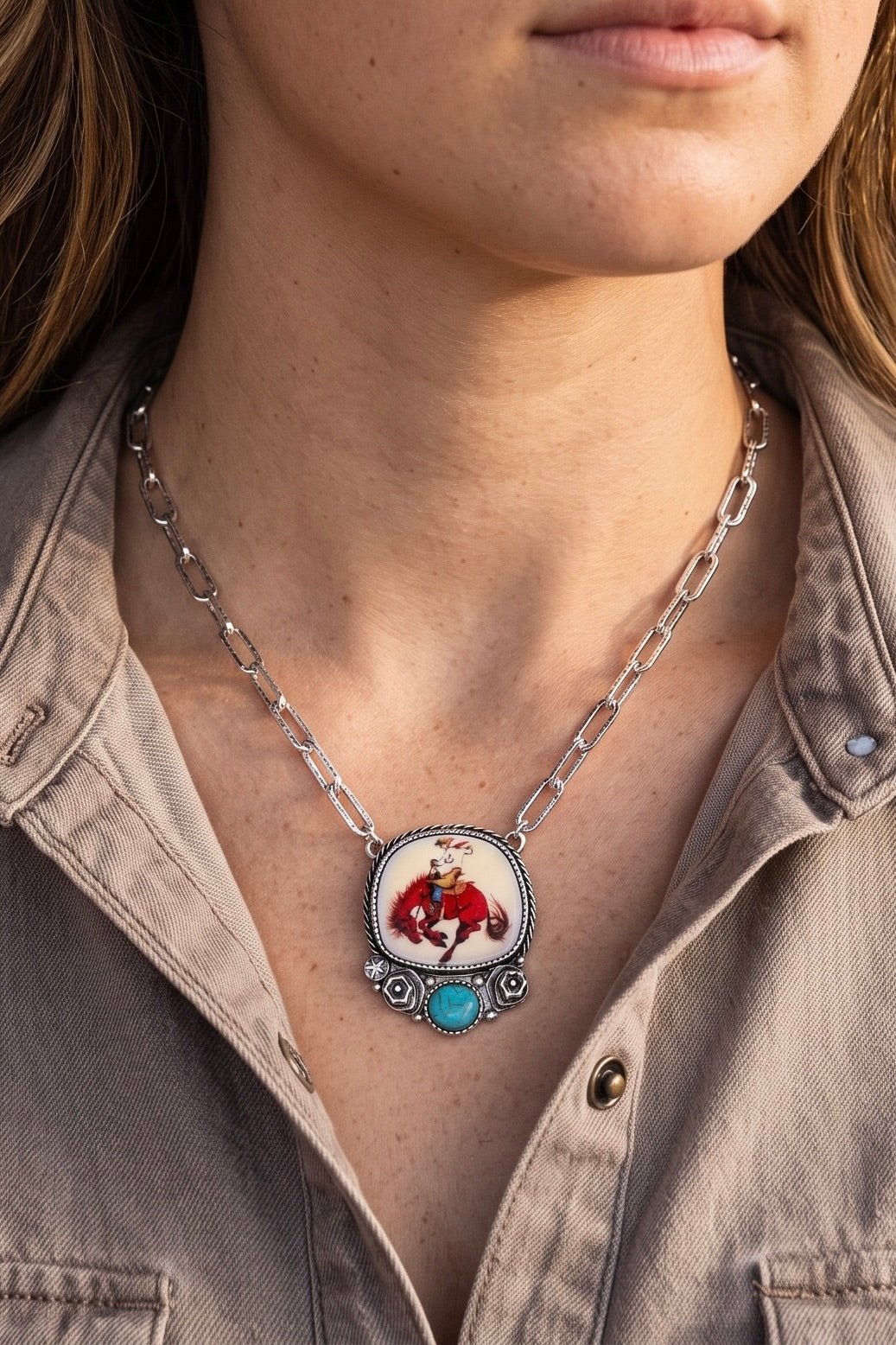 Western bronc rider pendant necklace with a turquoise-inspired stone accent on an antique silver paperclip chain.