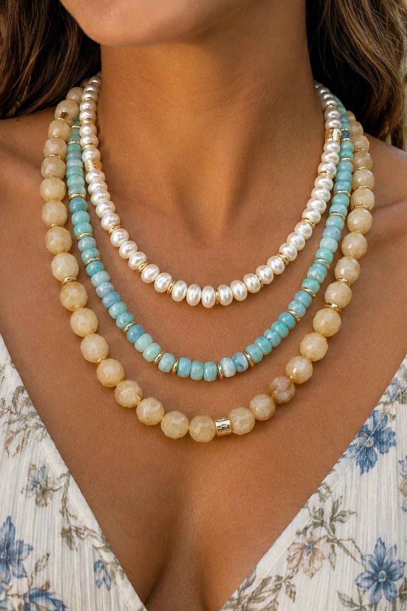 Three-strand layered beaded necklace featuring pale aqua beads, cream marbled beads, pearl-look beads and gold-tone spacer accents.