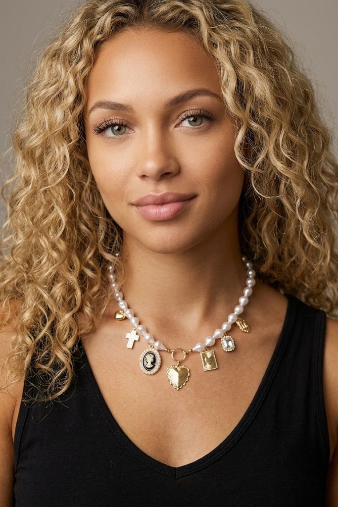 Vintage-inspired pearl charm necklace featuring heart, cross, cameo, and crystal charms on a delicate pearl chain, styled for romantic heirloom jewelry and feminine everyday fashion.