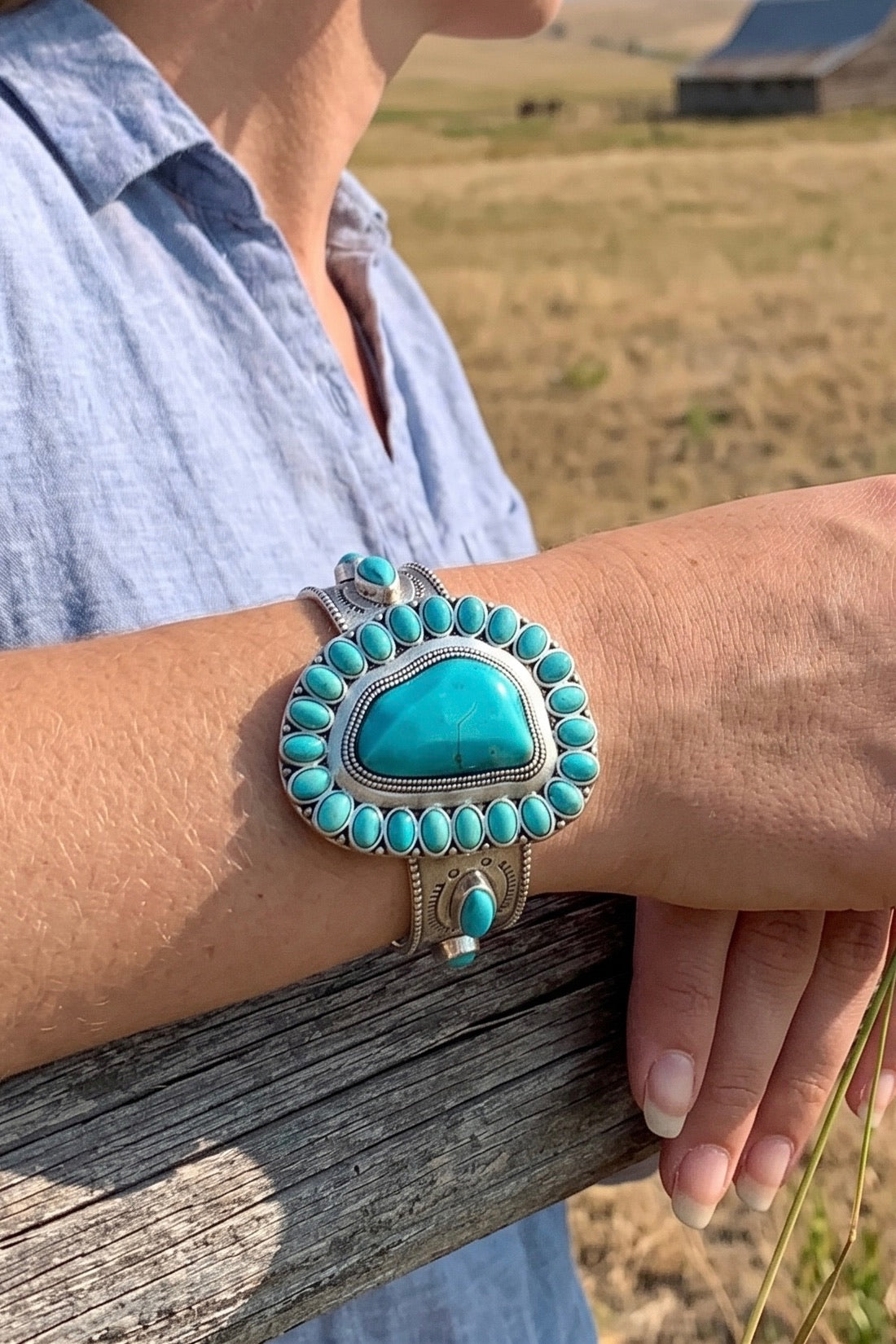 Southwestern turquoise cuff bracelet with a large center turquoise stone surrounded by smaller turquoise accents in an antique silver-plated C-shape design.
