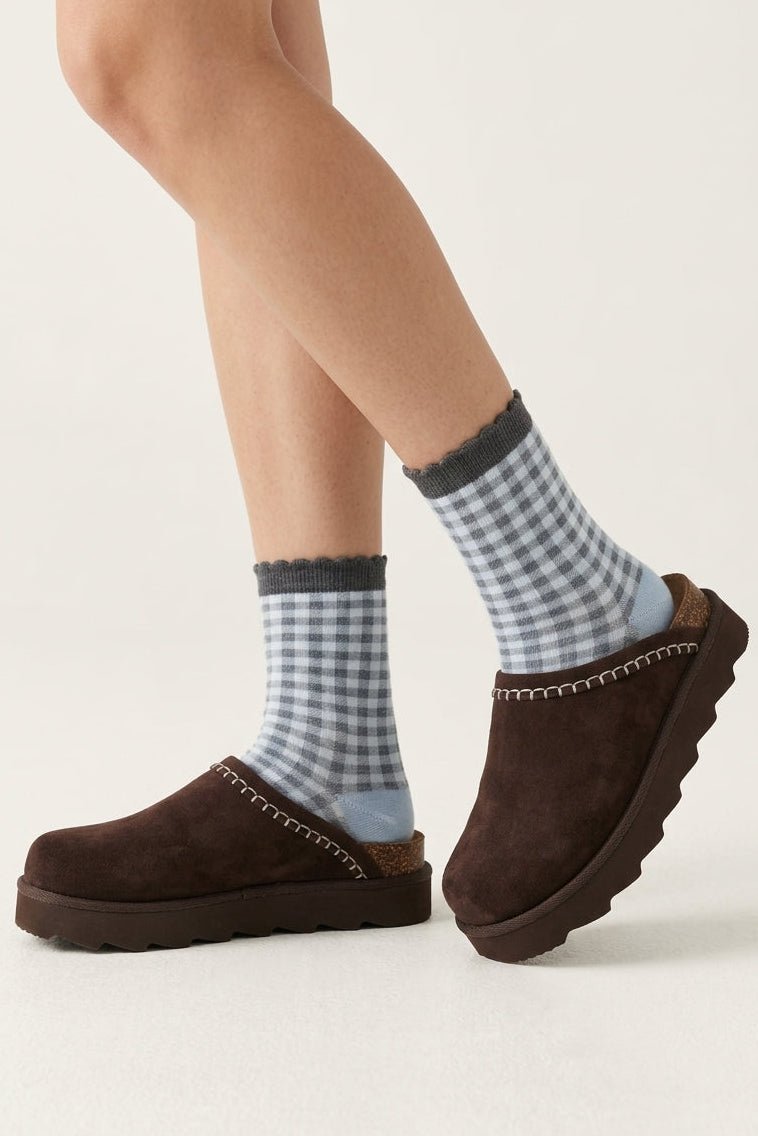 Brown suede platform clogs with contrast stitching, cork heel detail, and chunky lug soles styled with blue gingham socks.