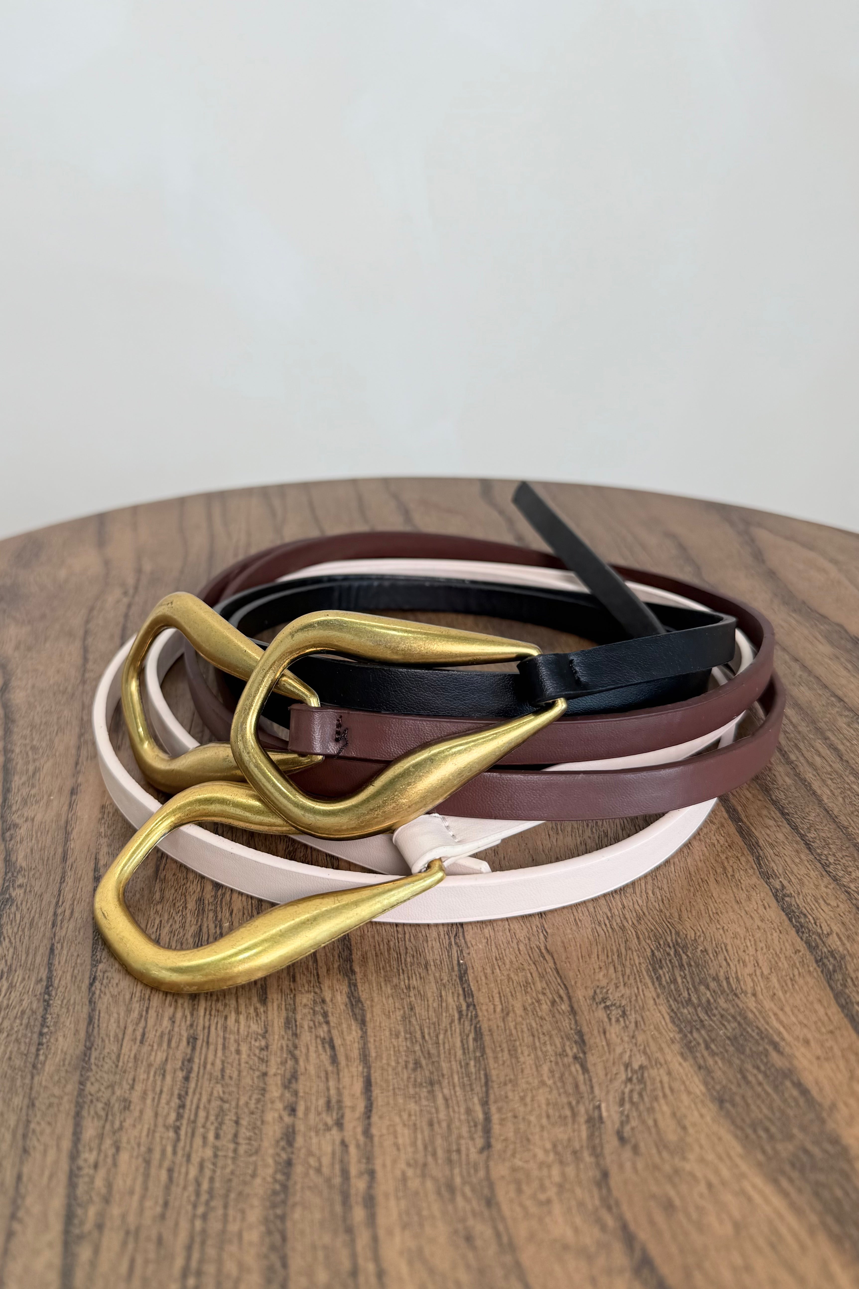 Thin leather belts in multiple colors with gold buckle knot detail