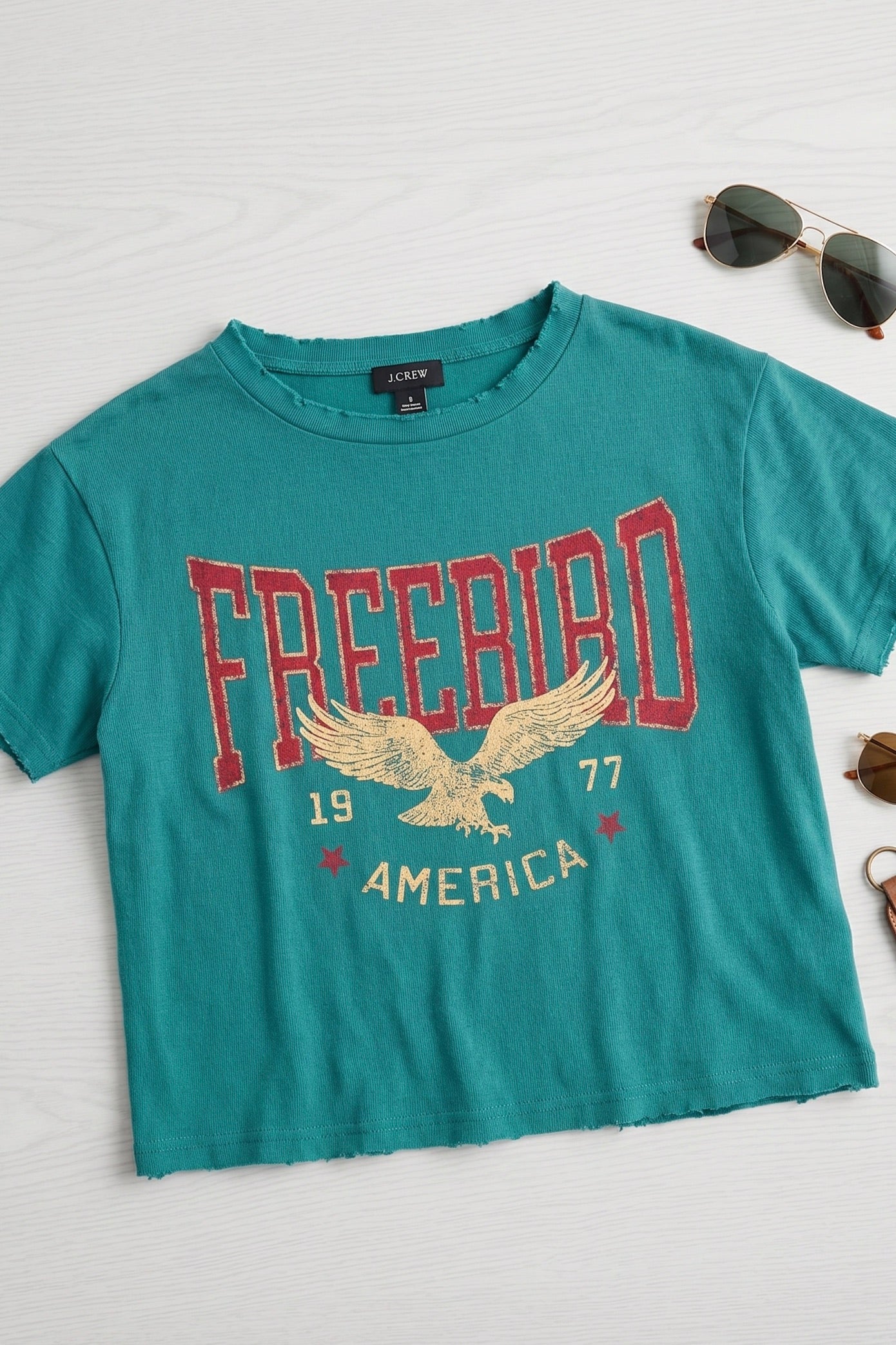 Women's teal vintage Free Bird America graphic tee featuring an eagle design, faux cropped silhouette, relaxed fit, and soft cotton fabric.