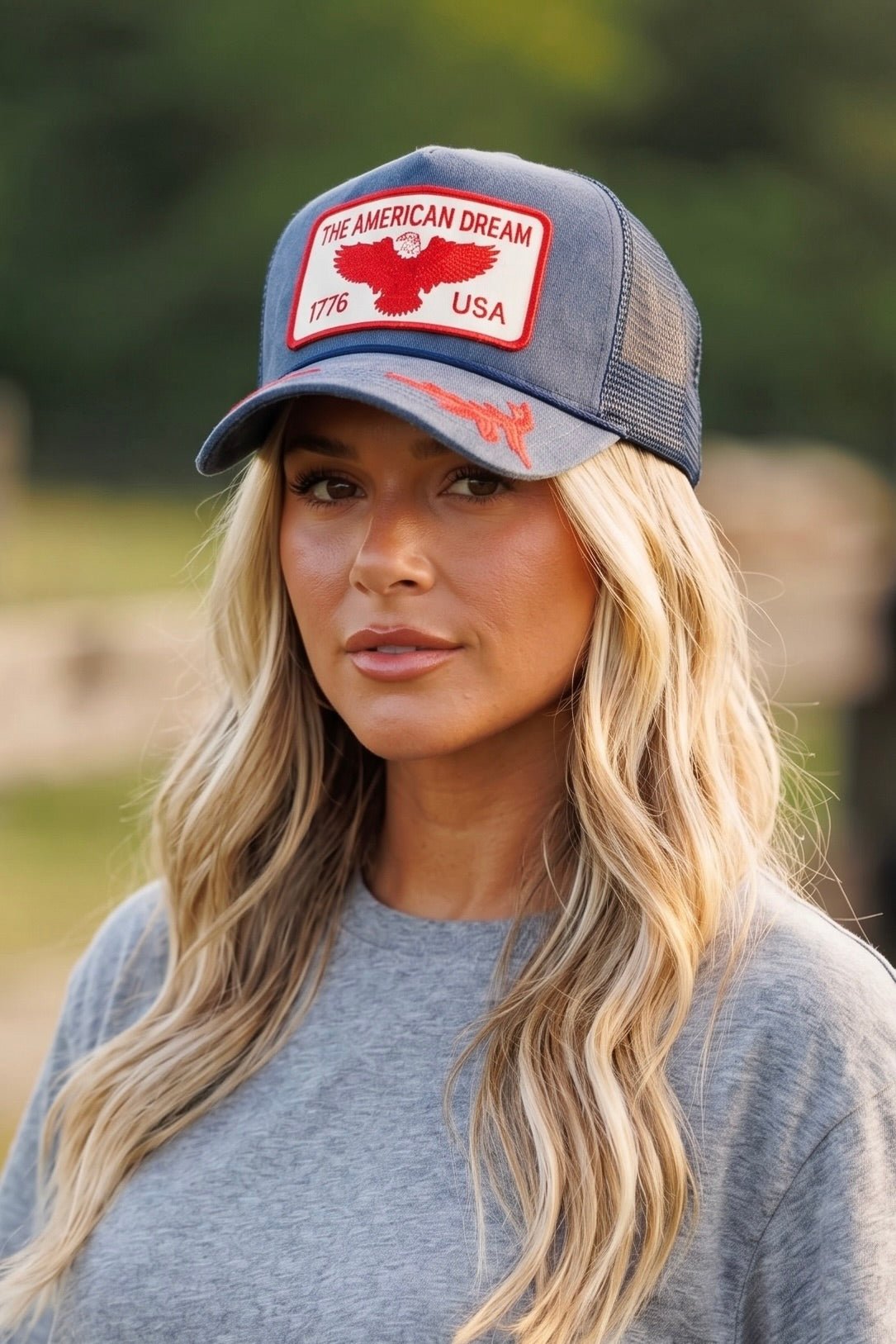 Vintage blue suede trucker hat featuring a red embroidered "The American Dream 1776 USA" eagle patch, red embroidered brim details, mesh back, and adjustable snapback closure.