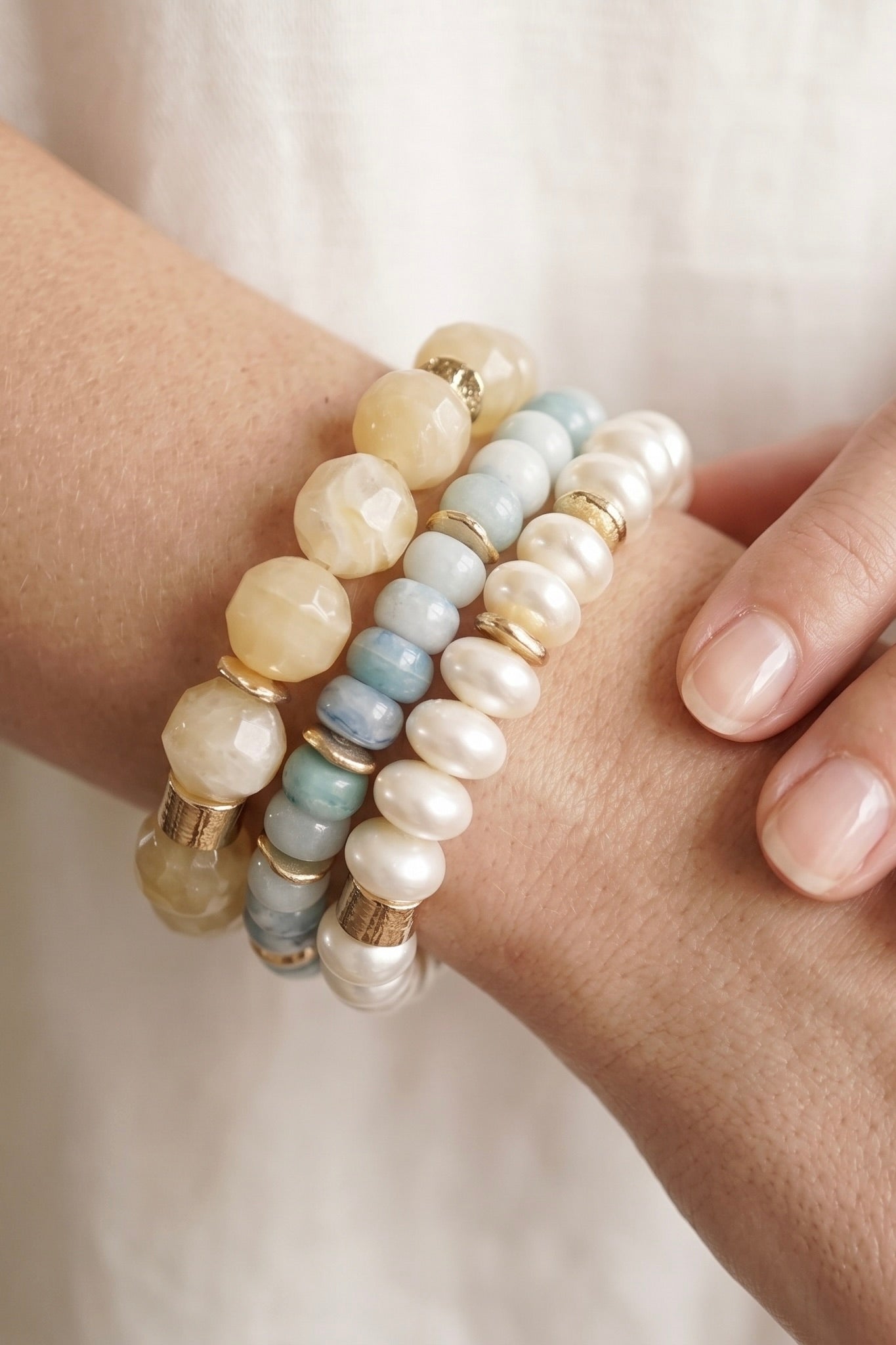 Seaside Glow three-piece stretch bracelet set with aqua beads, cream marbled beads, pearl-look beads and gold-tone accents.