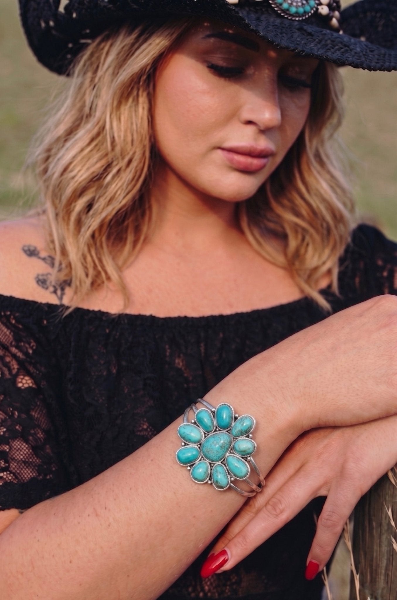 Turquoise cluster cuff bracelet with oval and teardrop stones set in silver, worn on wrist