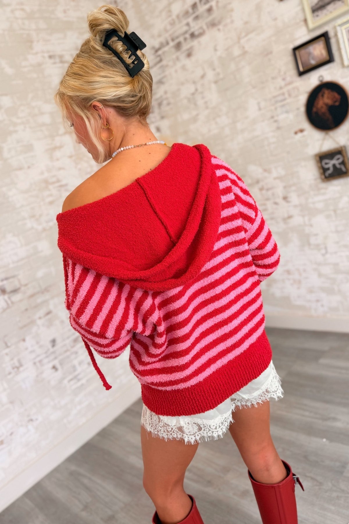 Women’s red and pink striped fuzzy knit zip-up hoodie featuring a soft textured finish, relaxed oversized fit, attached hood with drawstrings, front zipper closure, long sleeves, front pockets, and contrasting red ribbed cuffs and hem.