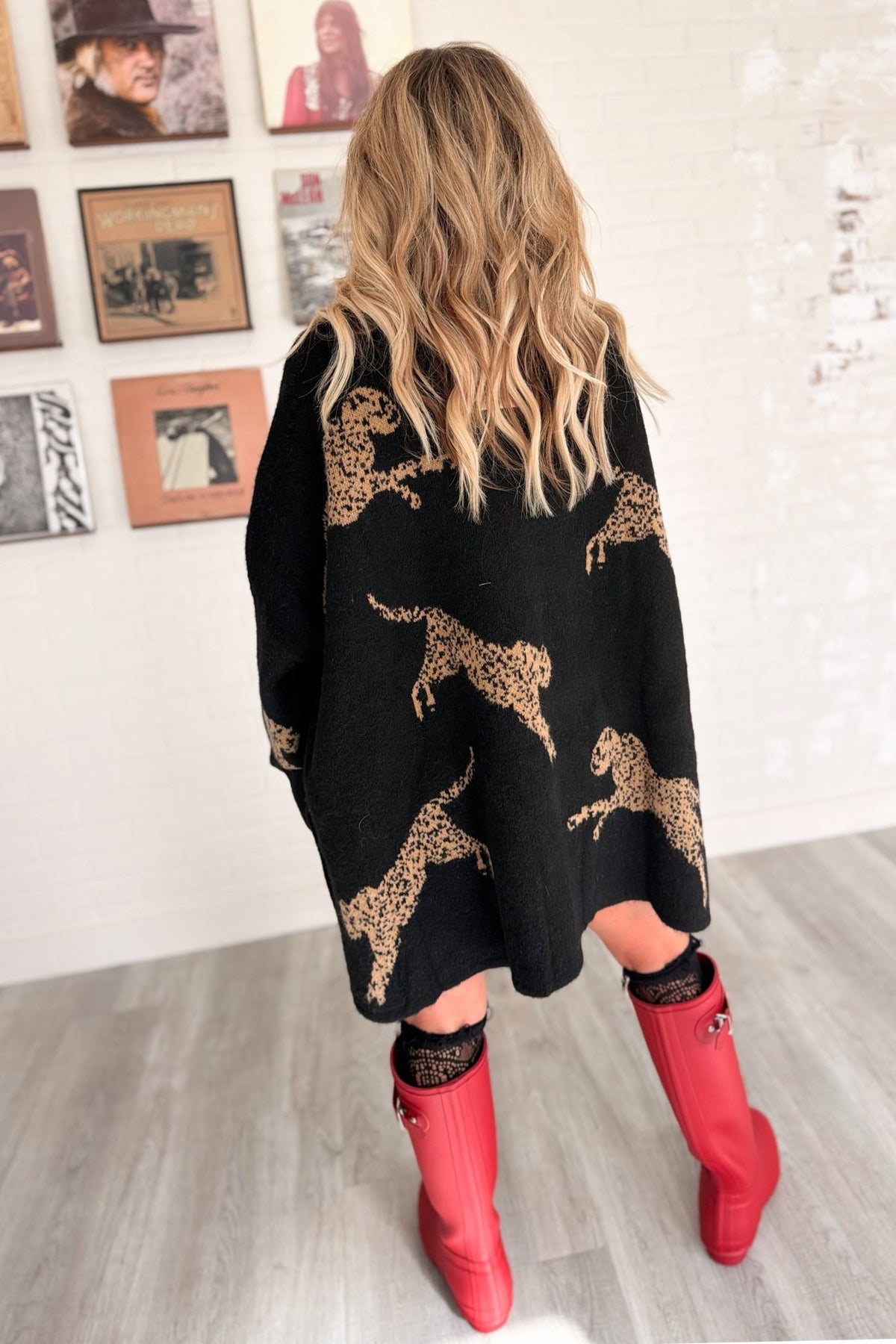 Women’s oversized black knit mock neck sweater featuring large camel cheetah animal motifs throughout, dropped shoulders, relaxed long sleeves, ribbed cuffs, and an extra-long tunic silhouette.
