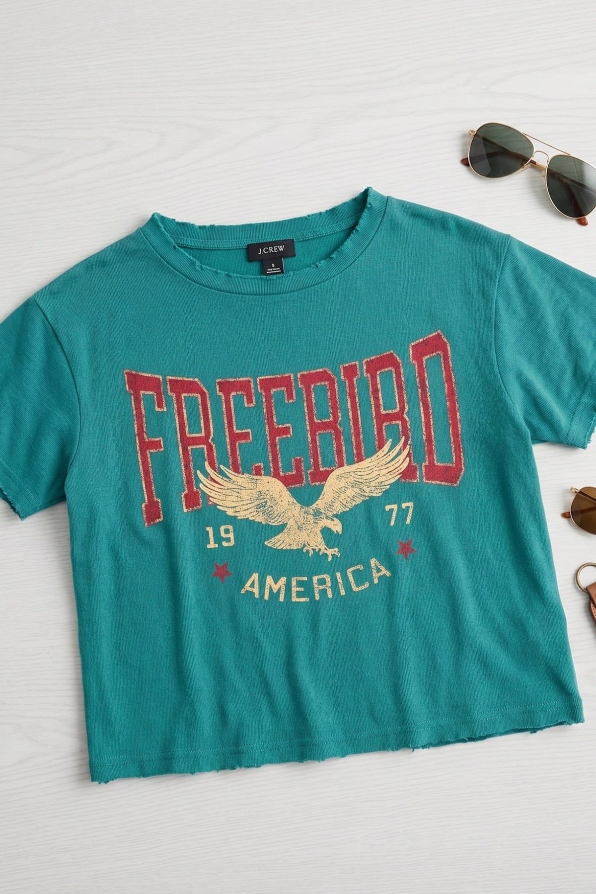 Women's teal vintage Free Bird America graphic tee featuring an eagle design, faux cropped silhouette, relaxed fit, and soft cotton fabric.