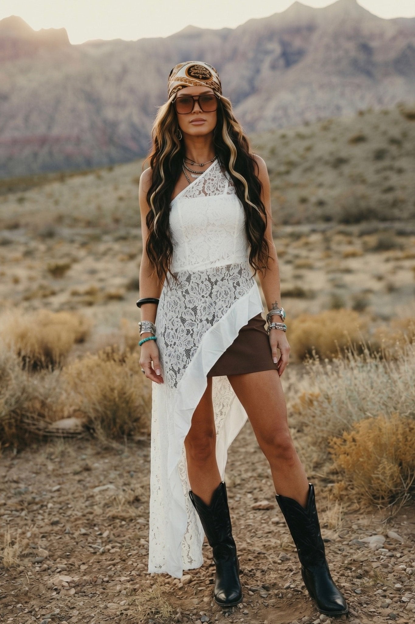 White one shoulder floral lace tunic top with an asymmetrical flowing hem paired with black wide leg pants.