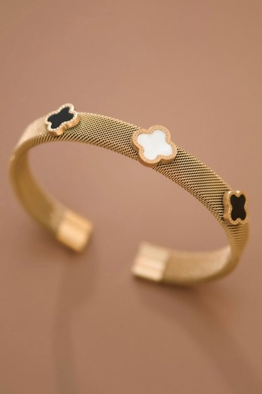 gold cuff with three clovers two black and one white