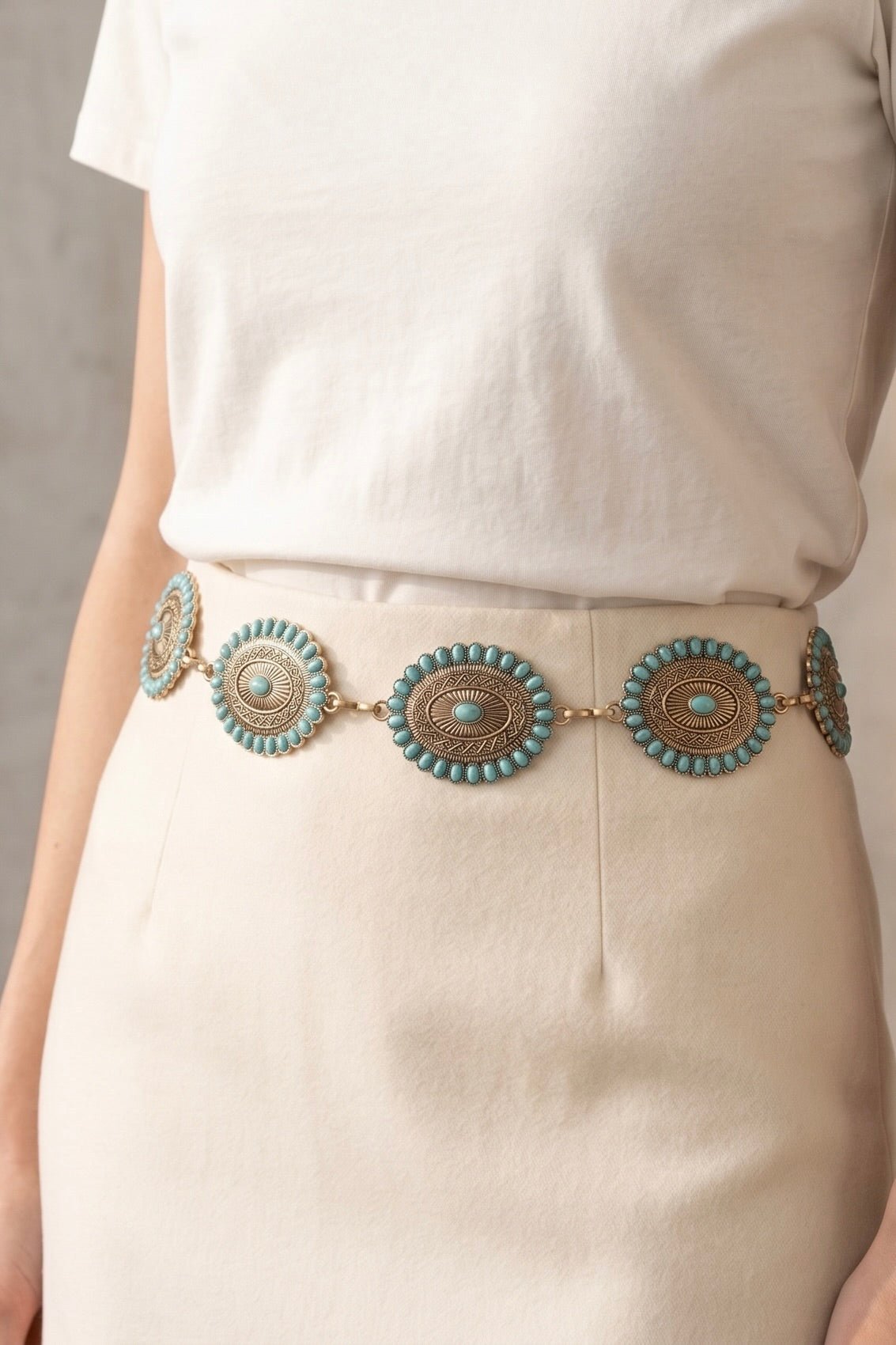 Western chain belt with antique gold oval conchos featuring turquoise stud accents, styled around a white skirt for a classic cowgirl-inspired look.