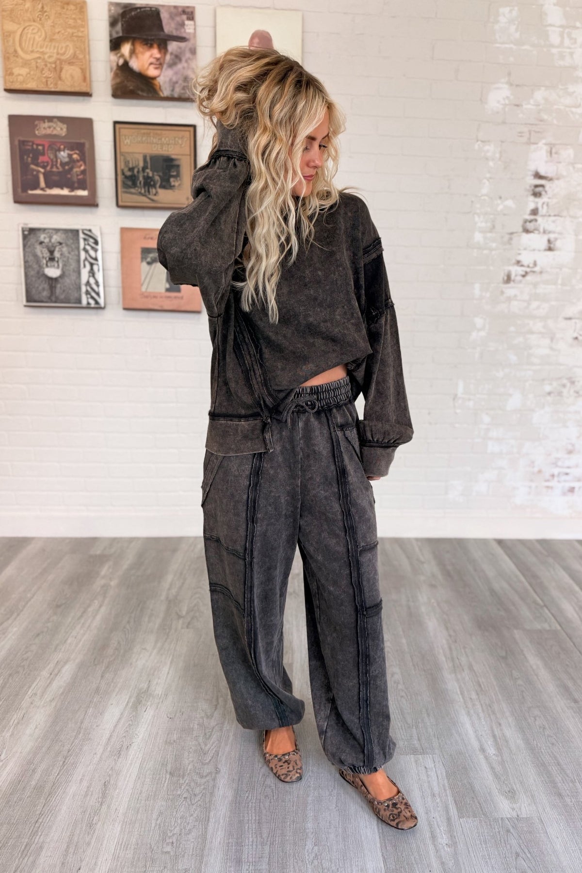 Women’s washed black mineral-washed two-piece lounge set featuring an oversized slightly cropped crewneck sweatshirt with exposed seam detailing and matching relaxed balloon jogger pants with an elastic drawstring waist, oversized patch pockets, exposed seams, and gathered ankles.