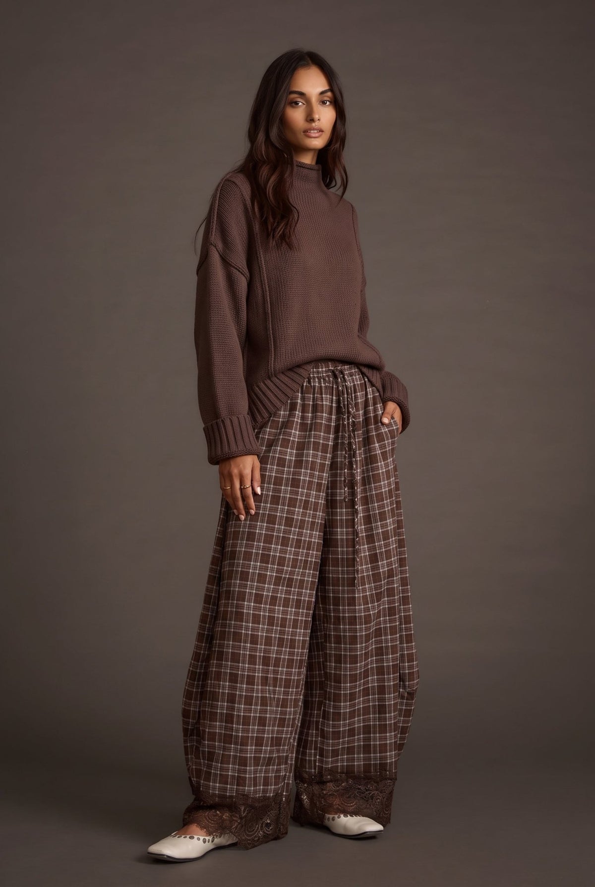 Women's brown and tan plaid wide-leg barrel pants featuring a relaxed, flowy silhouette, lightweight woven fabric, elastic waistband with adjustable drawstring, side pockets, and intricate chocolate brown floral lace trim along the hems. These boho-inspired, full-length plaid pants combine vintage romantic styling with a modern oversized fit, perfect for fall outfits, casual layering, and bohemian boutique fashion.