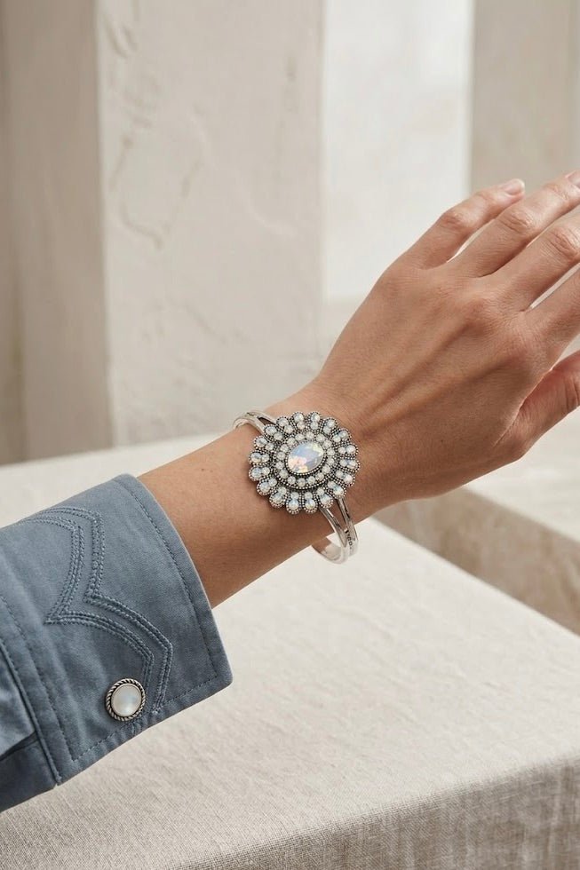 Silver cuff bracelet with a large round floral medallion design, featuring a central iridescent stone surrounded by small pearl-like accents