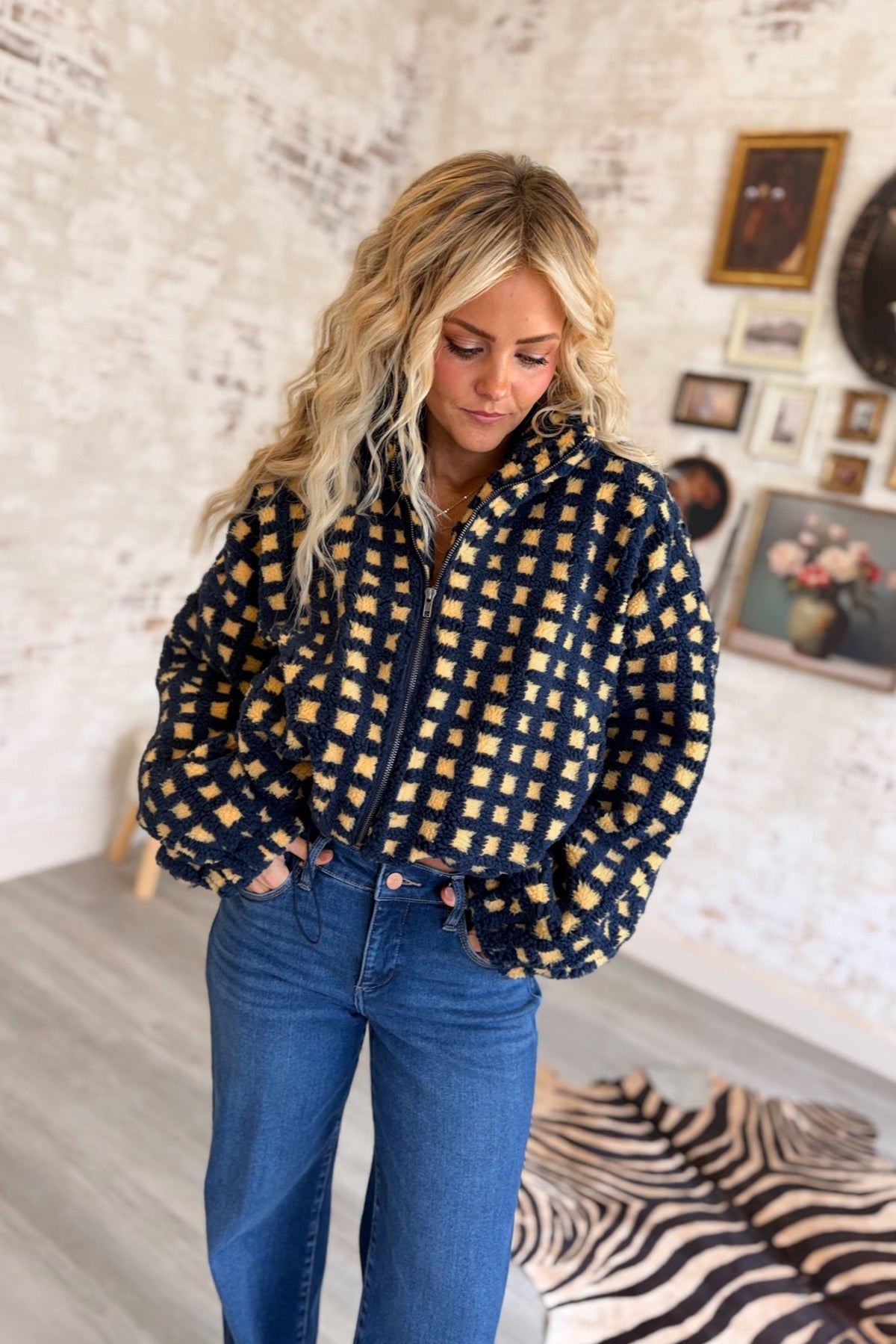 Women's navy blue and buttery yellow checkered sherpa fleece zip-up jacket featuring an allover gingham-inspired square pattern, plush textured teddy fabric, oversized relaxed silhouette, high stand collar, full front zipper closure, long voluminous sleeves with gathered elastic cuffs, and an adjustable drawstring hem for a customizable fit. This cozy, cropped-style sherpa jacket combines retro checkerboard styling with a playful, sporty aesthetic, perfect for casual fall outfits, winter layering, everyday 