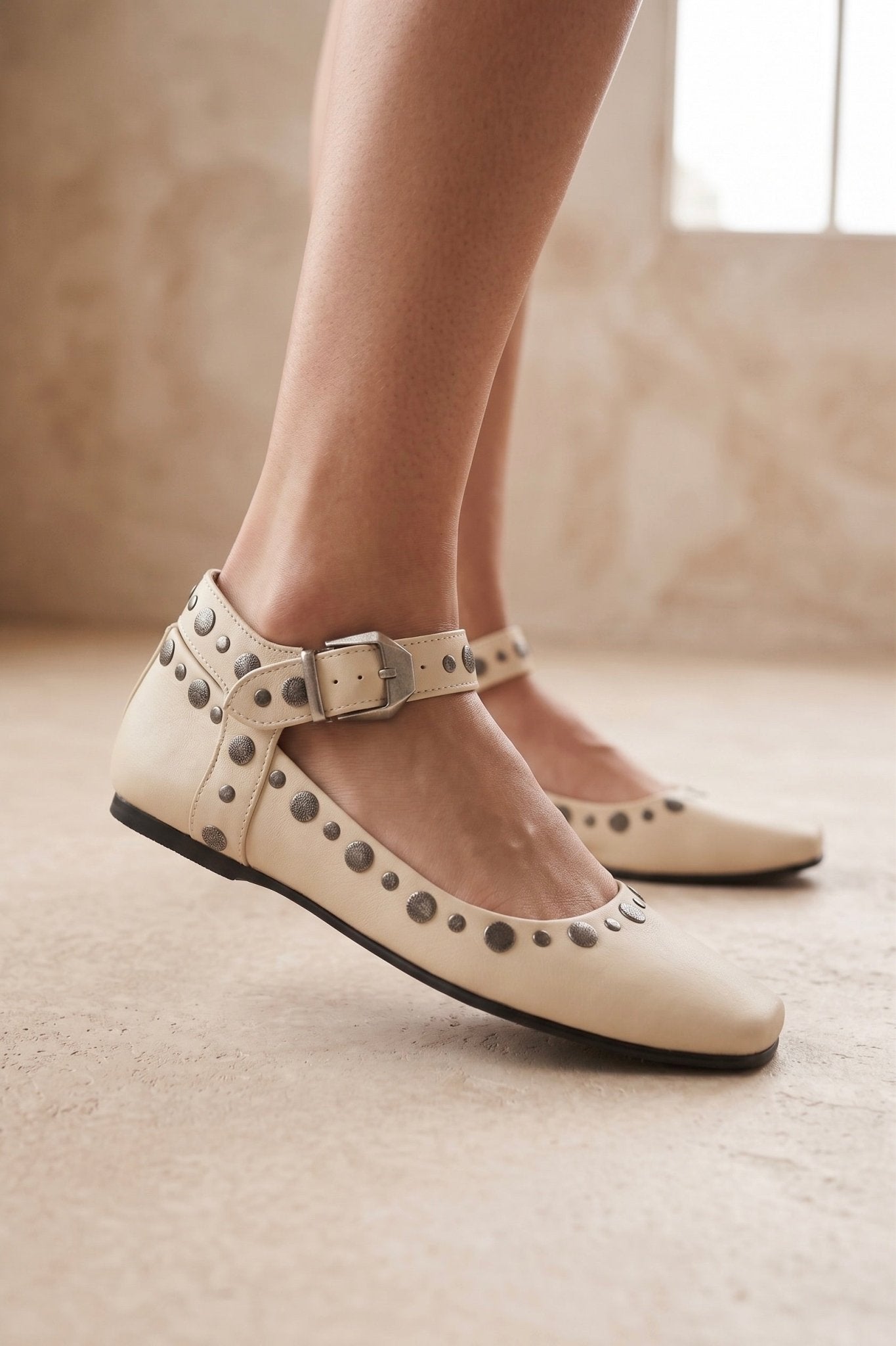 Ivory women’s square toe ballet flats with silver stud detailing, ankle straps and adjustable buckle closures.