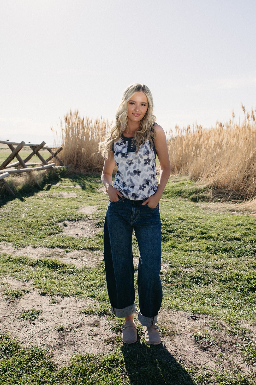 Lightweight sleeveless floral henley tank top styled with denim for summer outfits, lake day looks, country concert nights, beach town vacations, rodeo weekends, casual BBQ outfits, and effortless boho western summer fashion from Sand + Charcoal Boutique.
