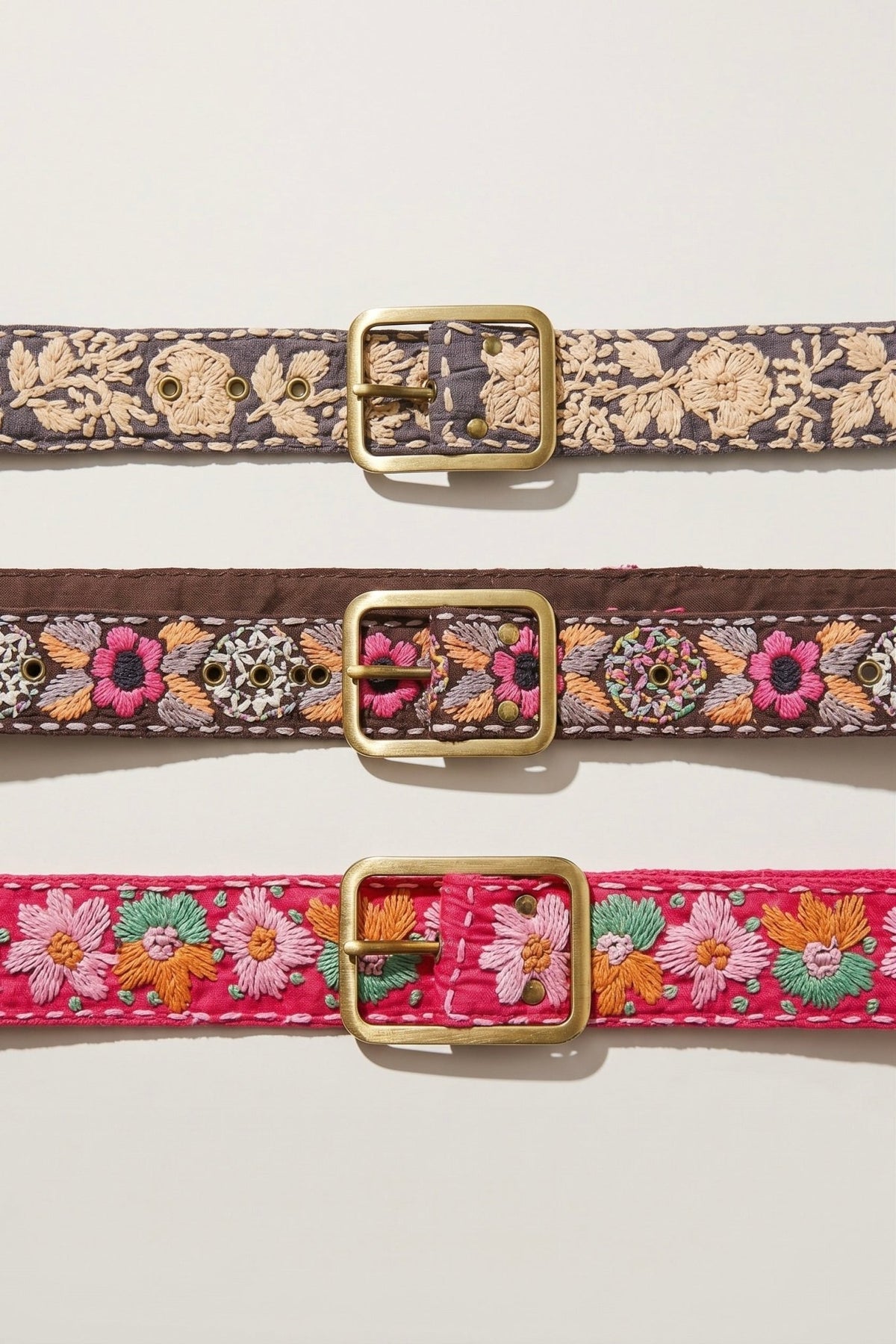 Brown embroidered fabric belt with pink, orange, grey and ivory stitched details and antique gold-tone metal buckle.