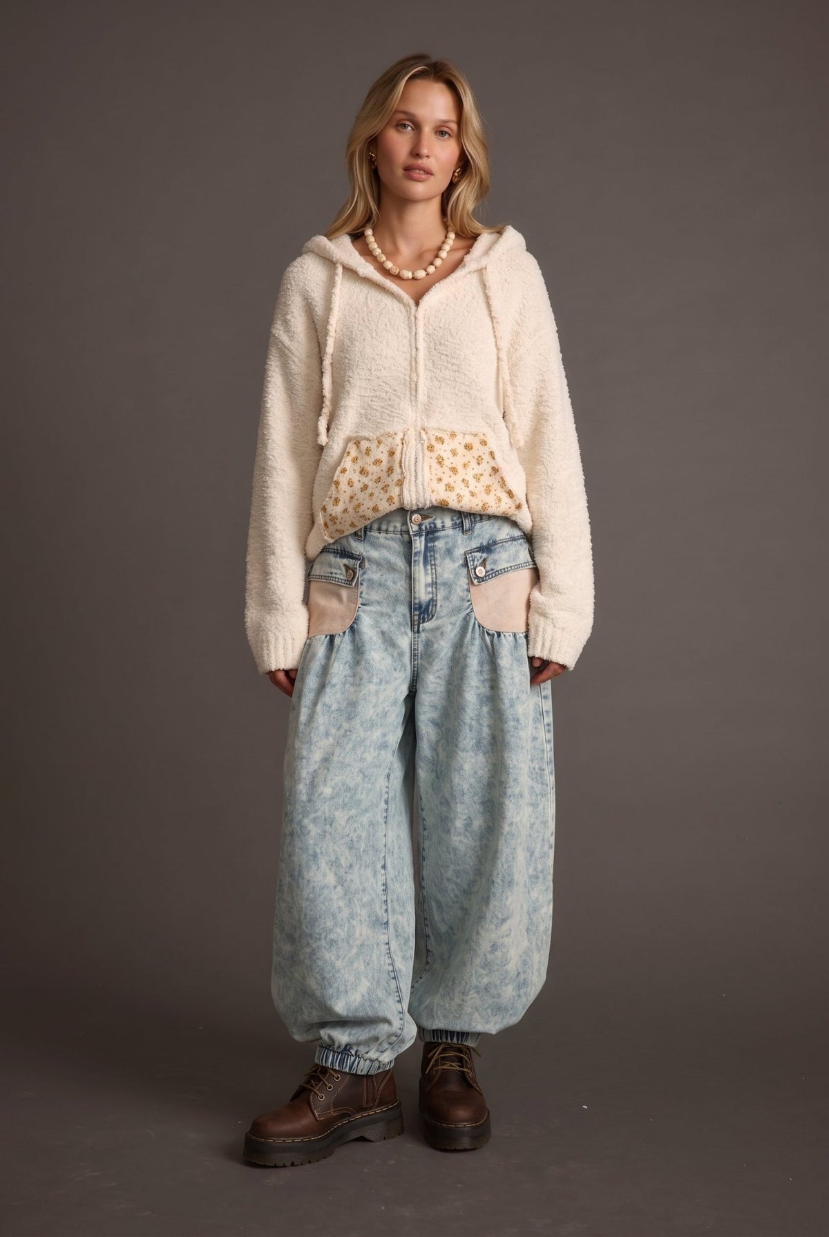 Woman wearing light wash acid wash denim barrel leg jeans with an oversized wide-leg silhouette and contrast front pocket details, styled with a cream knit sweater.