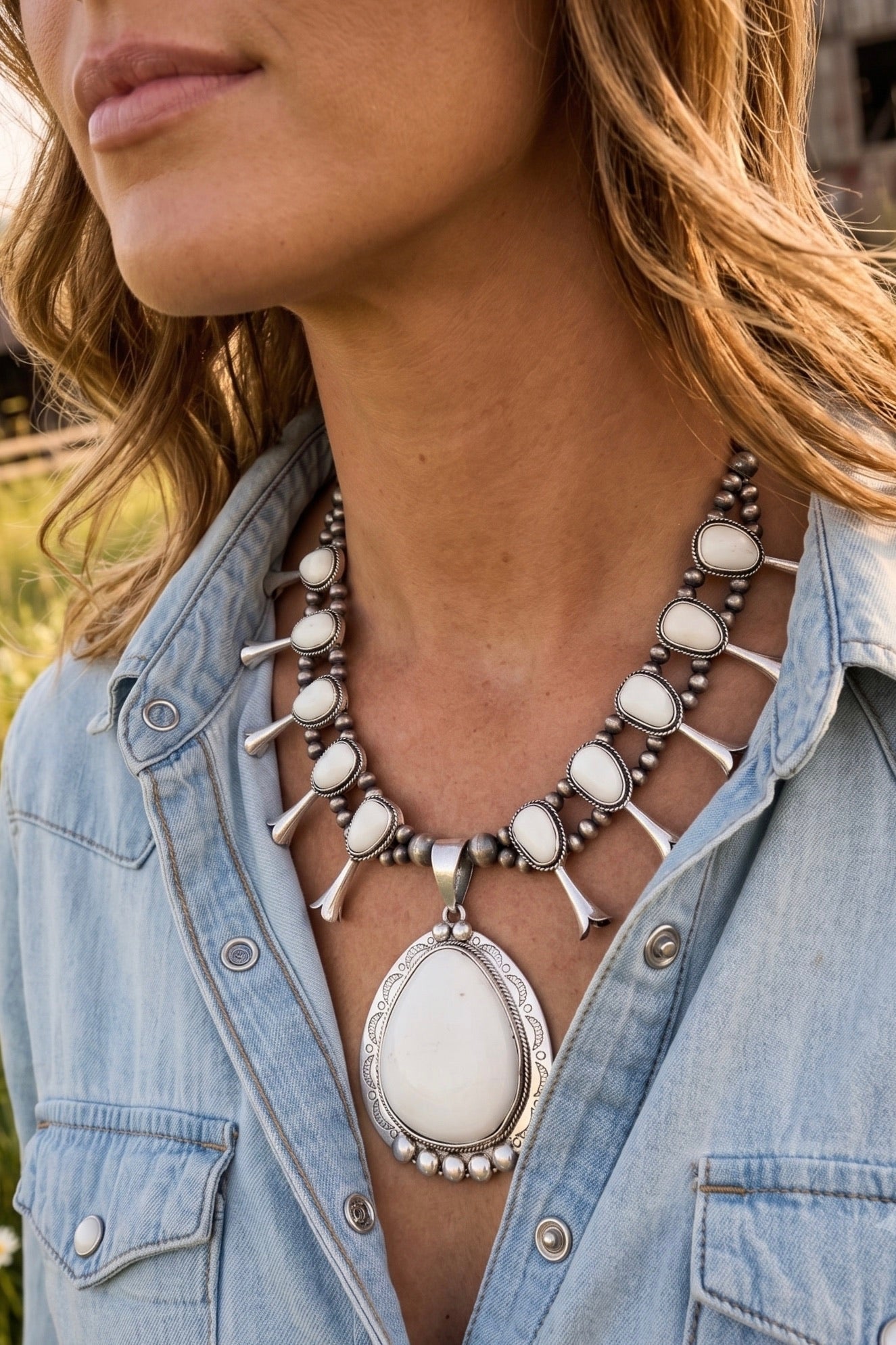 Handmade white turquoise squash blossom necklace with antique silver-plated details and an oversized western statement pendant styled with a denim shirt.