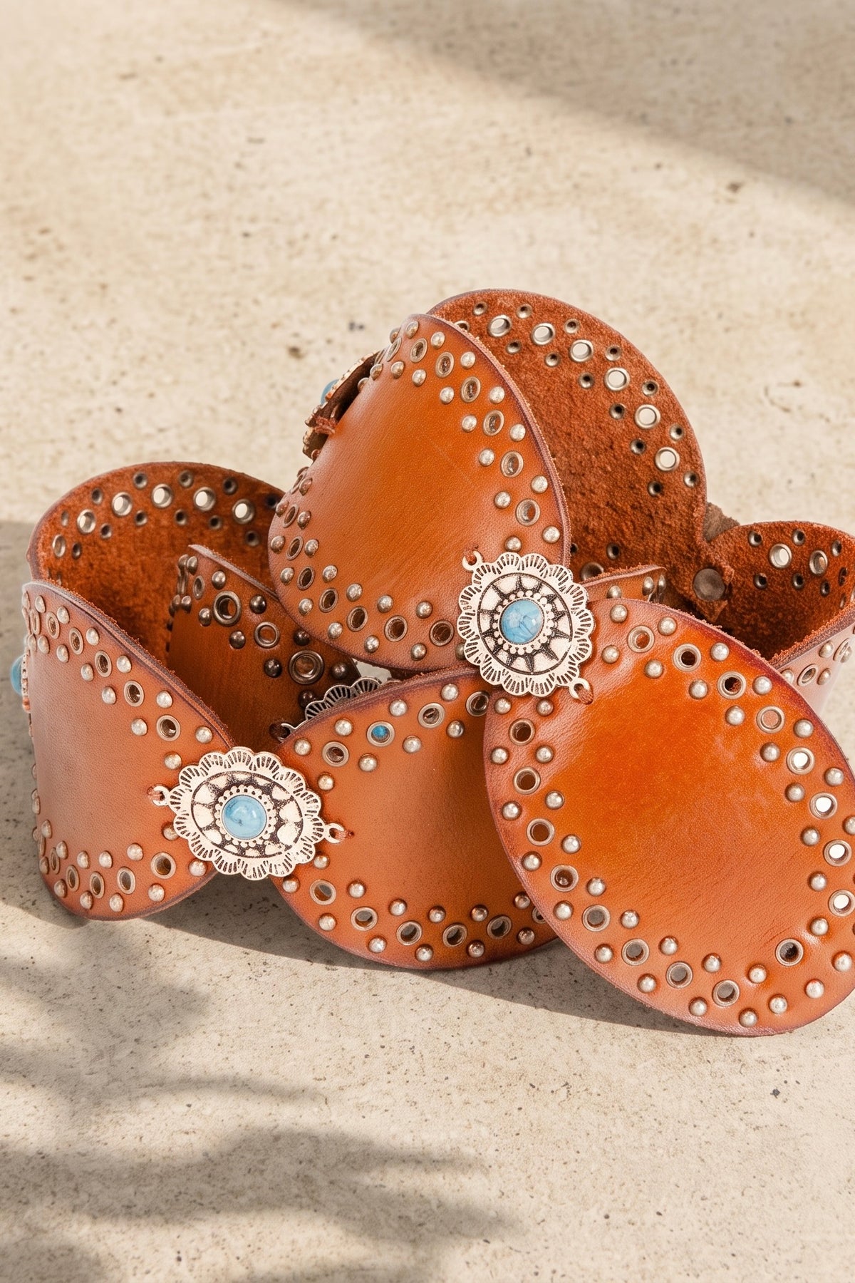 Women’s caramel brown leather western statement belt with studded oval medallions and turquoise concho accents